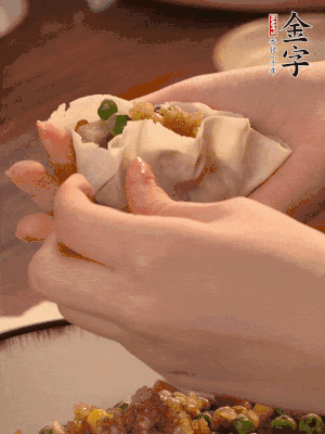 取一大勺餡料放進(jìn)餃子皮里，用大拇指按住頂部餡料，再用虎口掐出形狀。