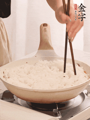 把瀝干水分的米飯均勻鋪在上面，筷子戳幾個(gè)洞，以便透氣，轉(zhuǎn)小火蓋上蓋子燜至水分收干，大概10分鐘。